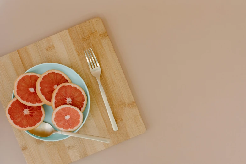 a plate of grapefruits and a spoon on a cutting board, pexels contest winner, minimal pink palette, rendered in 4 k, eats bambus, miranda meeks
