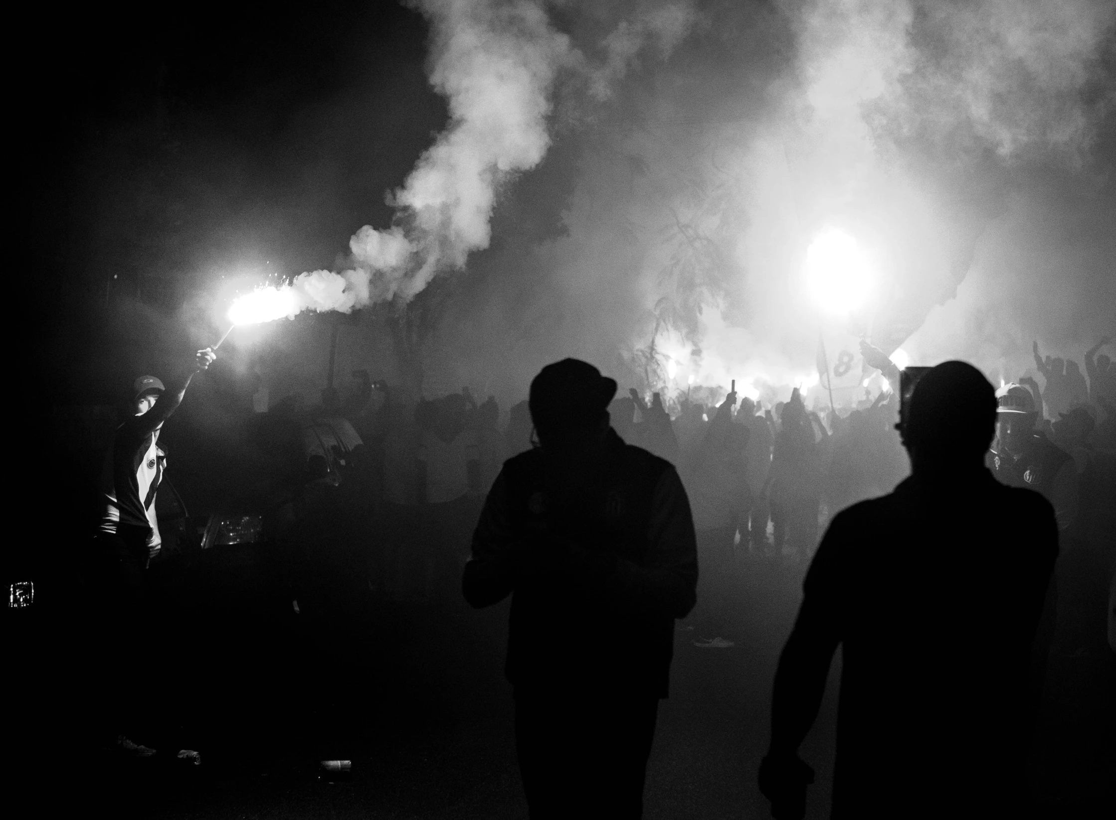 a group of people that are standing in the dark, a black and white photo, by Anato Finnstark, pexels, sots art, tear gas and smoke, crowded silhouettes, flares, mod