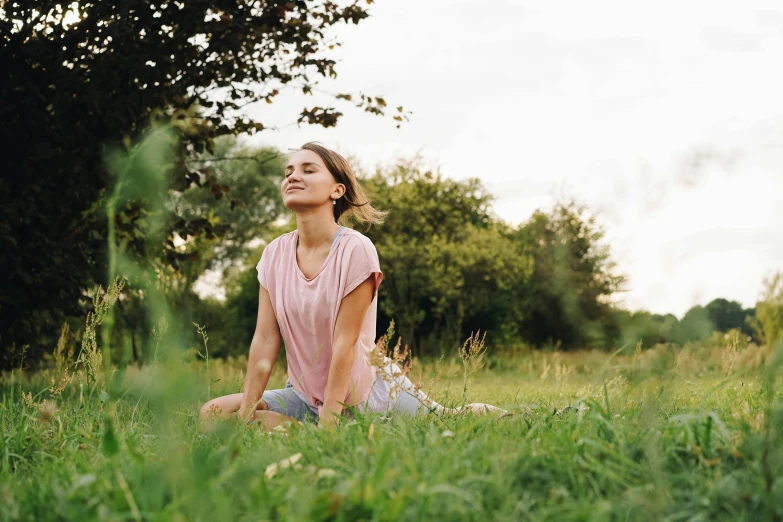 a young woman is sitting down in a grassy field