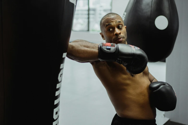 a man standing next to a punching bag, by Carey Morris, pexels contest winner, square, in fighter poses, profile image, thumbnail