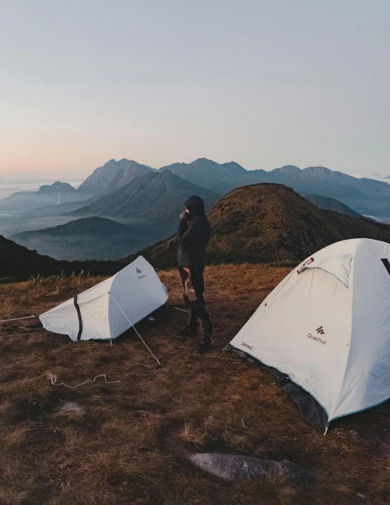 a couple of tents sitting on top of a hill, profile image