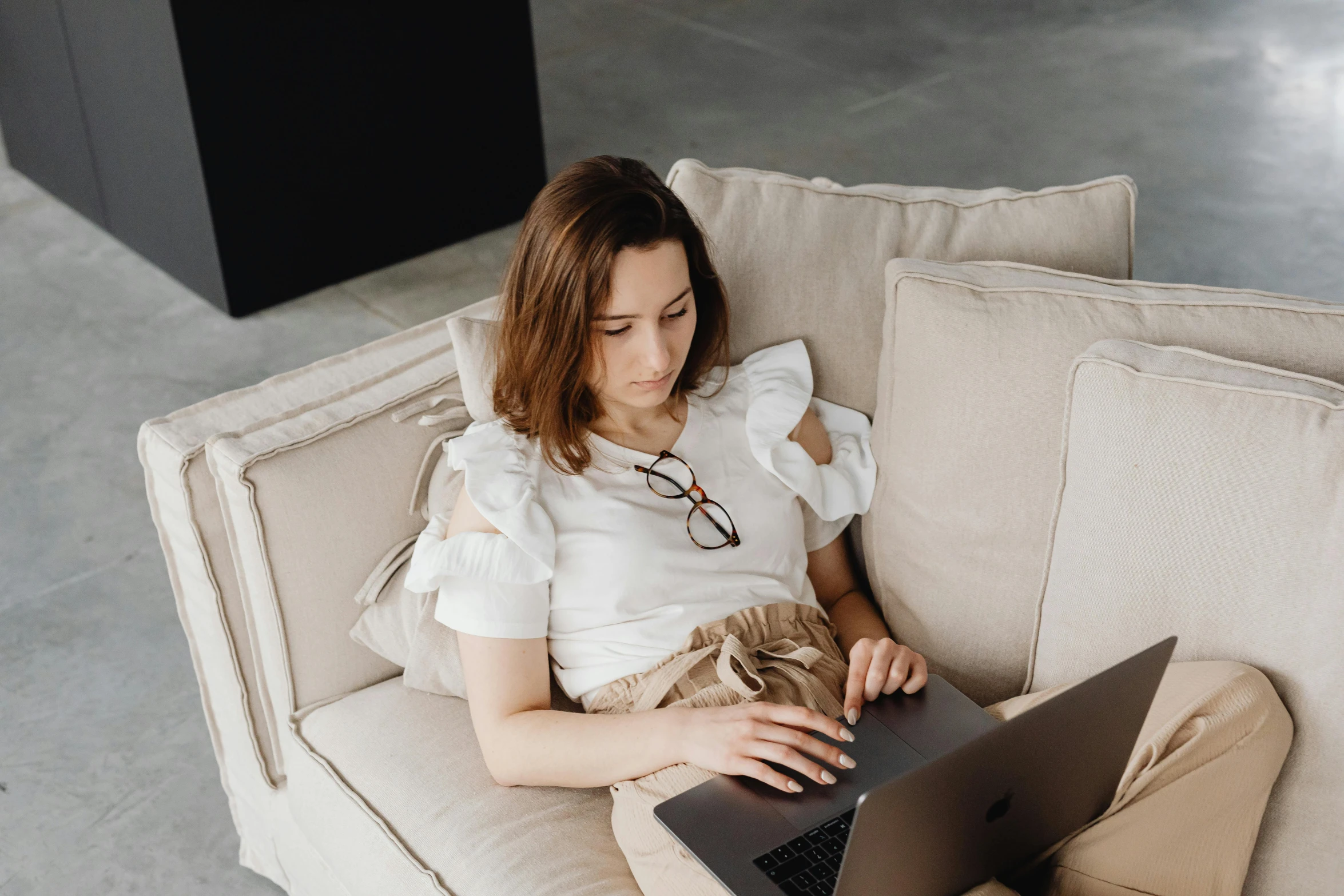 a woman sitting on a couch using a laptop, trending on pexels, renaissance, girl with brown hair, wearing a linen shirt, avatar image, white sleeves