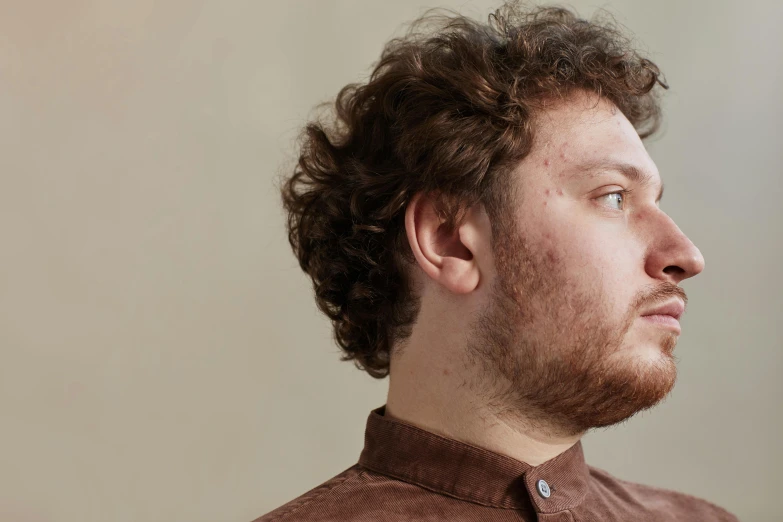 a young man with brown hair looks away from the camera