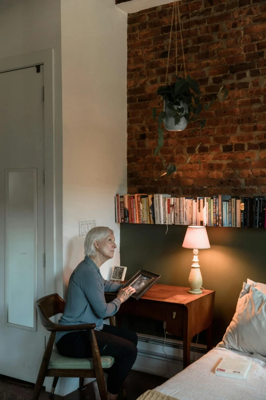 an old lady sitting on a chair and looking at a picture book