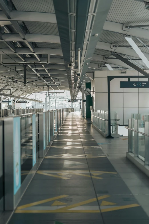 an empty train station with a yellow arrow painted on the floor, unsplash, skybridges, crowded airport, panoramic shot, square