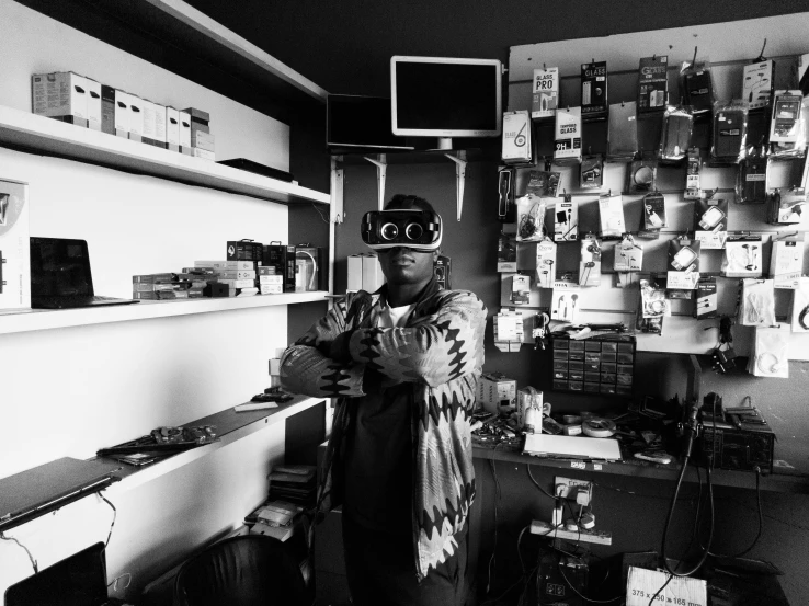 a black and white photo of a man in a room, afrofuturism, vr googles, standing in his cluttered garage, it specialist, photo for a store