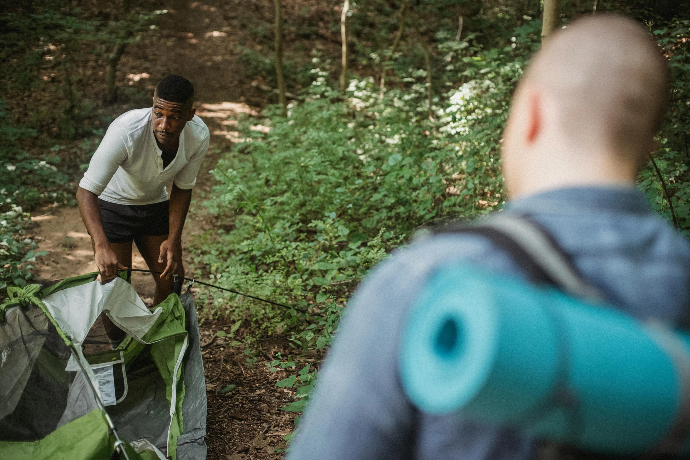 a man standing next to a tent in the woods, by Sebastian Spreng, lying on the woods path, everyone having fun, promo image, humans exploring