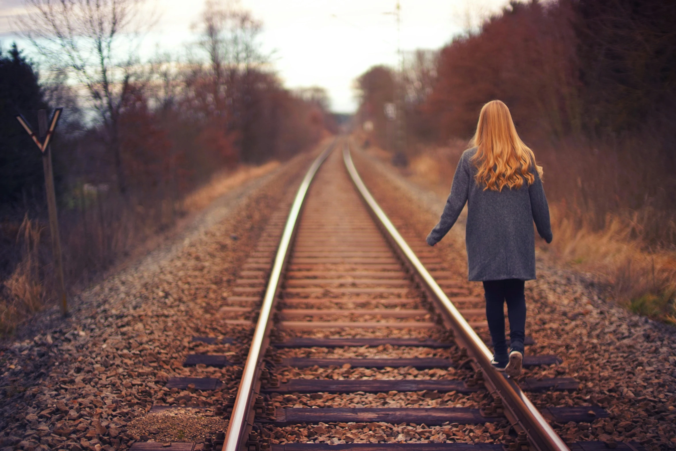 a woman is walking down the train tracks, pexels contest winner, realism, long ginger hair, heartbreak, ellie bamber, small steps leading down