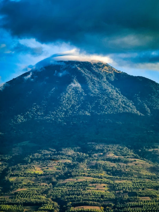 a large cloud hangs over the mountains on a blue day