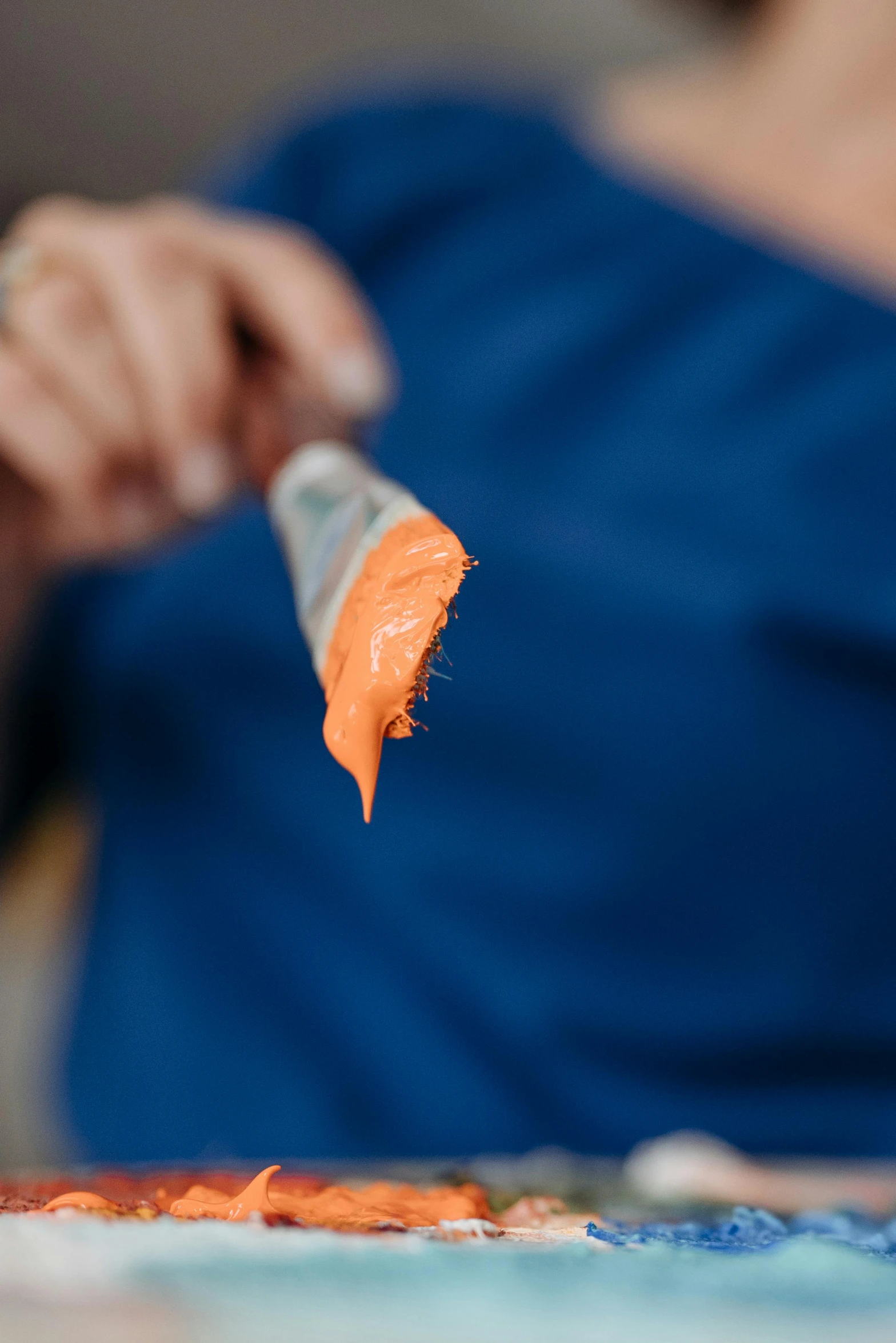 a close up of a person holding a paint brush, dark blue + dark orange, ready to eat, lynn skordal, blue orange