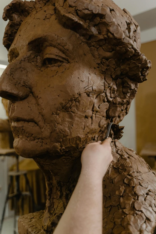 a close up of a clay sculpture of a person, a bronze sculpture, inspired by Diego Giacometti, reddit, chocolate art, italian renaissance workshop, square facial structure, digging