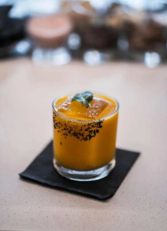 a glass filled with a drink sitting on top of a table, mango, thumbnail, dessert, charred