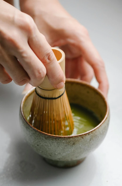 a person is stirring a green liquid in a small container