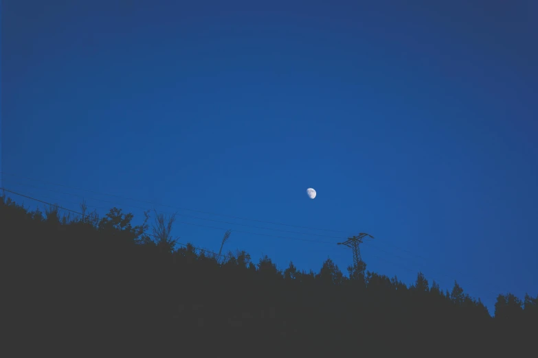 a full moon in a blue sky over a forest, unsplash, postminimalism, ☁🌪🌙👩🏾, evening lights, rectangle, 🌲🌌