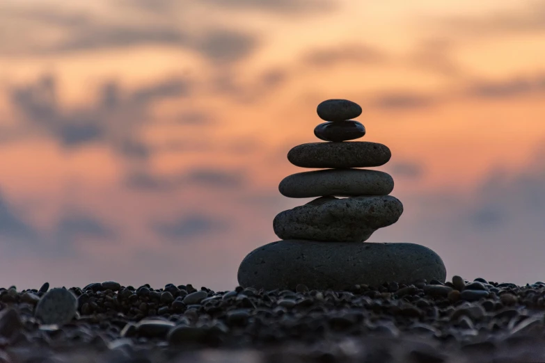 a stack of rocks sitting on top of a rocky beach, unsplash, minimalism, at dusk lighting, healthcare, stone statue, instagram post