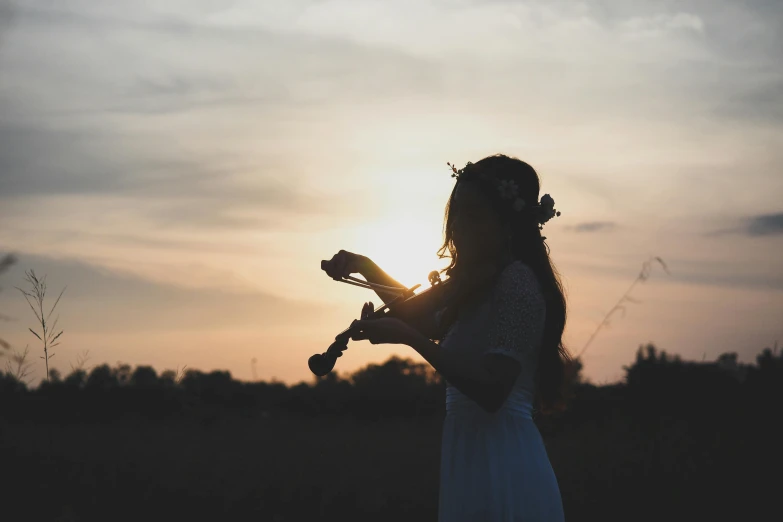 a woman in a white dress playing a violin, pexels contest winner, romanticism, silhouettes in field behind, young girl playing flute, 15081959 21121991 01012000 4k, sunset halo around her head