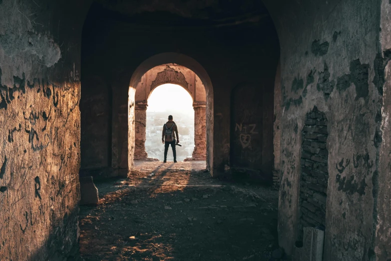 a person standing at the end of a tunnel, pexels contest winner, romanticism, city ruins in the background, back lit, doorway, overlooking