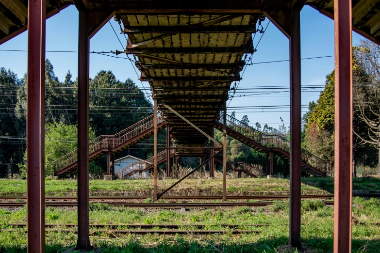 a train station sitting next to a lush green field, an album cover, by Yasushi Sugiyama, unsplash, mingei, “derelict architecture buildings, stairs and arches, in karuizawa, collapsed floors