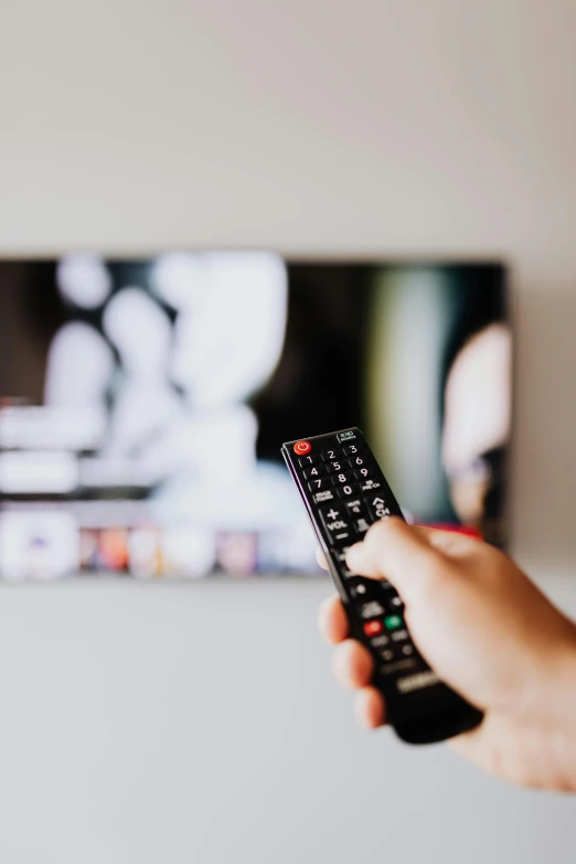 a person holding a remote control in front of a television, pexels, curated collections, belgium, promotional image, multiple stories