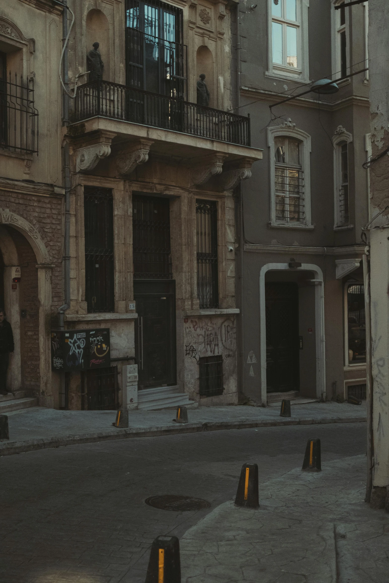 a man riding a skateboard down a street next to tall buildings, a picture, by Constantine Andreou, pexels contest winner, neoclassicism, location of a dark old house, gif, entrance, brown