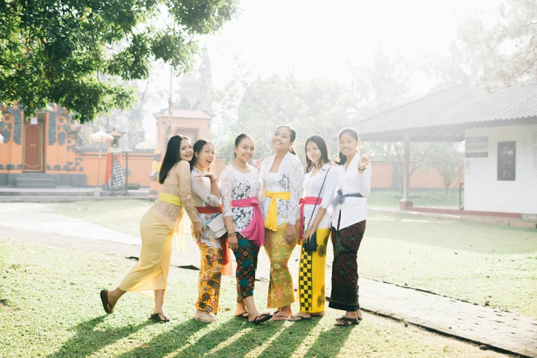 a group of women standing on top of a lush green field, inspired by I Ketut Soki, pexels contest winner, wearing festive clothing, standing in a buddhist temple, city morning, 🦩🪐🐞👩🏻🦳