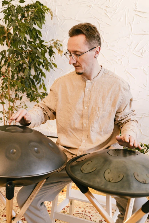 a man playing steel pans in a living room, an album cover, inspired by Aladár Körösfői-Kriesch, unsplash, on a pale background, domes, healing pods, close up portrait shot