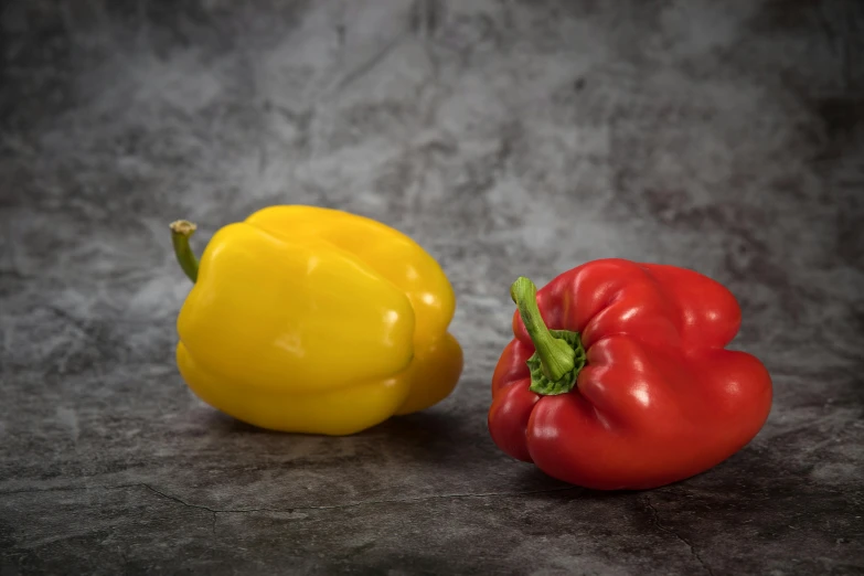 two peppers sitting next to each other on a table, coloured gel studio light, 6 pack, hansa yellow, on grey background