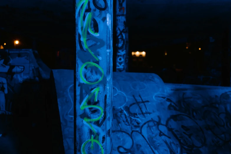 a man riding a skateboard up the side of a ramp, inspired by Elsa Bleda, unsplash, graffiti, blue bioluminescence, graffiti in an abandoned bunker, neon pillars, closeup photograph