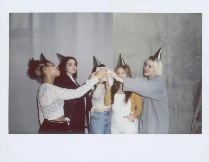 a group of women standing next to each other, a polaroid photo, tumblr contest winner, fluxus, wearing a party hat, off - white collection, cheers, wears a light grey crown