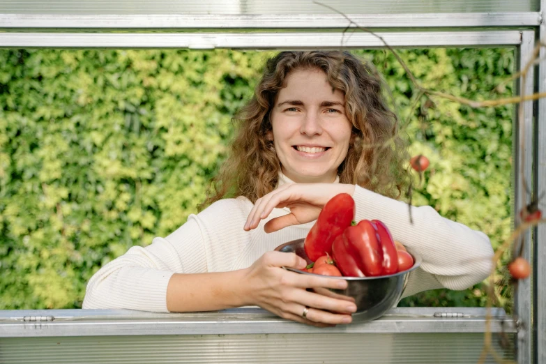 a woman holding a bowl of red peppers, by Juriaen van Streeck, pexels contest winner, desert white greenhouse, avatar image, looking happy, britt marling style 3/4