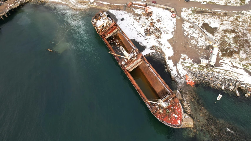 a large boat sitting on top of a body of water, a digital rendering, pexels contest winner, scrapyard, drone footage, taken in the early 2020s, oil spill