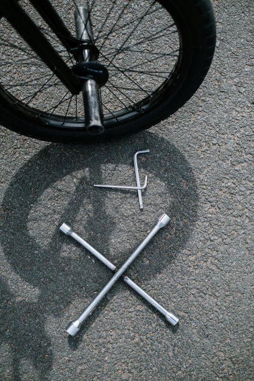 a bicycle that is laying on the ground, an album cover, by Jacob Toorenvliet, unsplash, assemblage, wrenches, hinged titanium legs, cross hatch, circle pit