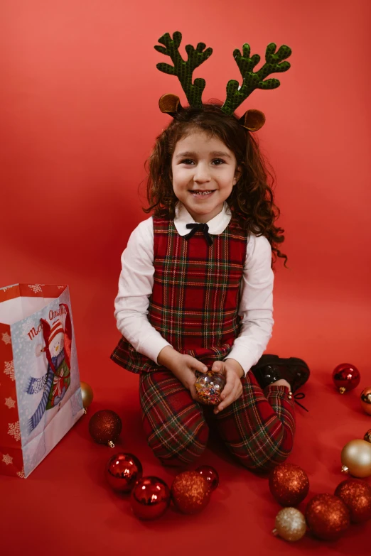 a  in reindeer costumes sitting by christmas ornaments