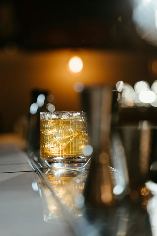 a glass filled with liquid sitting on top of a counter, speakeasy, thumbnail, gold hour, multiple stories