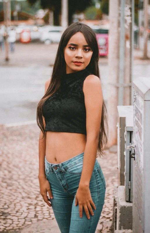 a girl wearing tight jeans poses in a black crop top