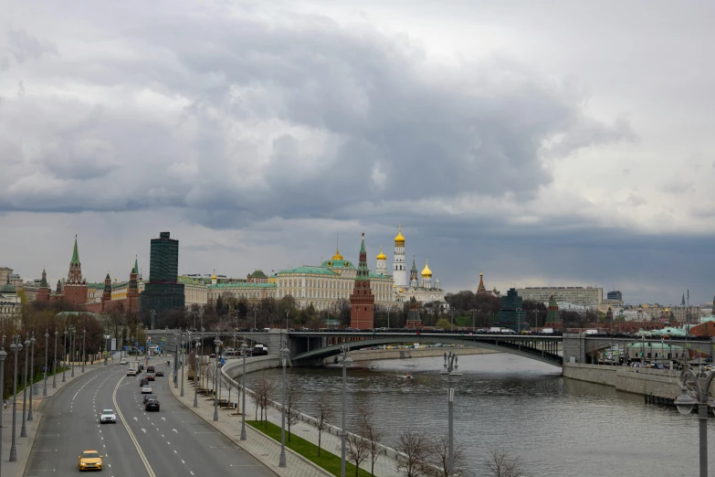 a group of cars driving down a road next to a river, inspired by Vasily Vereshchagin, pexels contest winner, socialist realism, moscow kremlin, gray clouds, all buildings on bridge, 000 — википедия