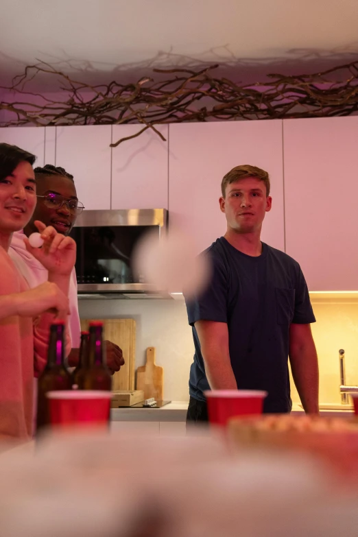 a group of friends socializing in a crowded kitchen