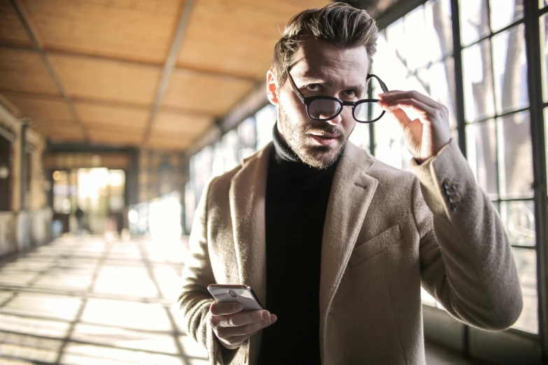 a man looking at his cellphone in front of an open window