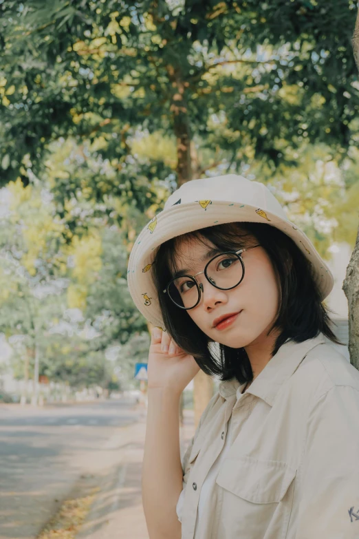 a woman in a hat and glasses leaning against a tree, by Tan Ting-pho, unsplash contest winner, realism, square rimmed glasses, male ulzzang, ☁🌪🌙👩🏾, girl cute-fine-face