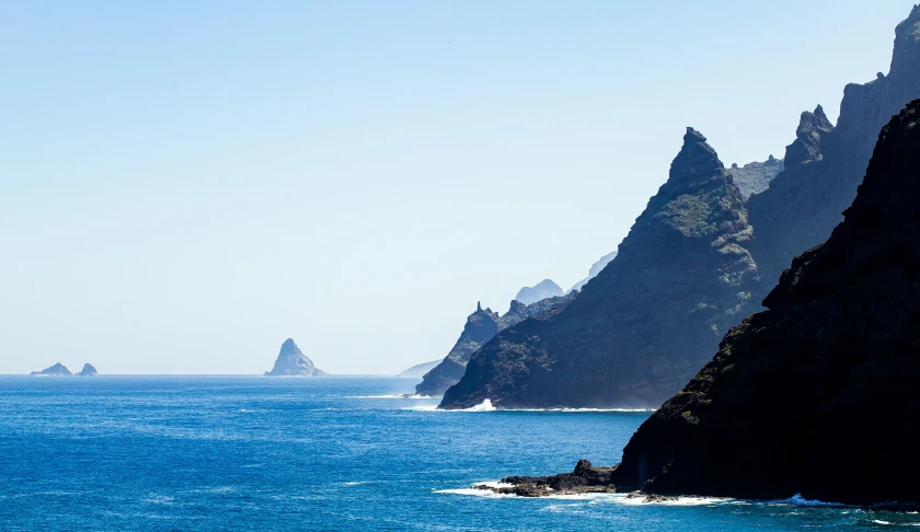 a boat floats across an island, surrounded by mountains