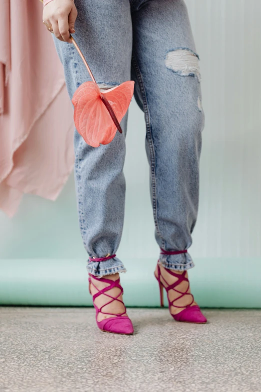 woman with pink high heels and pink handbag holding a blue red and black umbrella