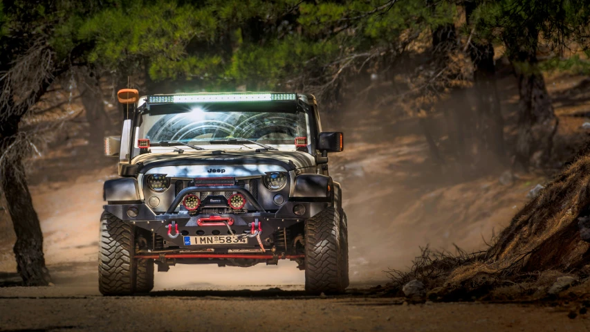 a jeep driving down a dirt road next to trees