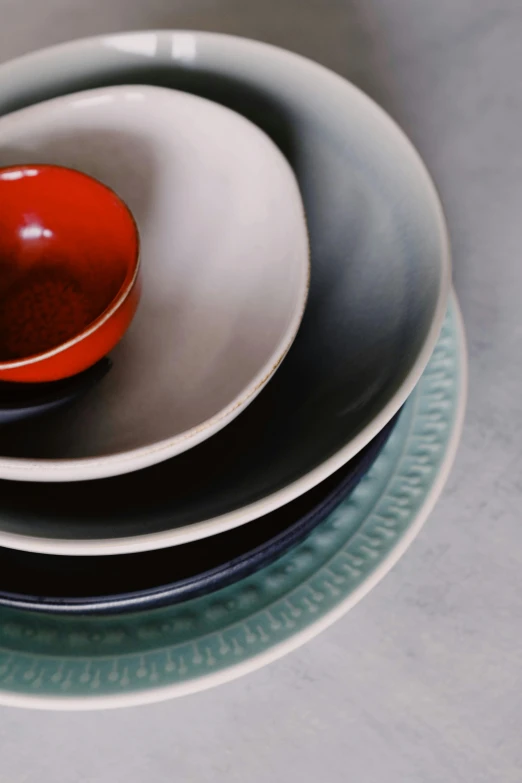 a stack of plates sitting on top of each other, a still life, by Fuller Potter, unsplash, viridian and venetian red, medium closeup, made of glazed, grey