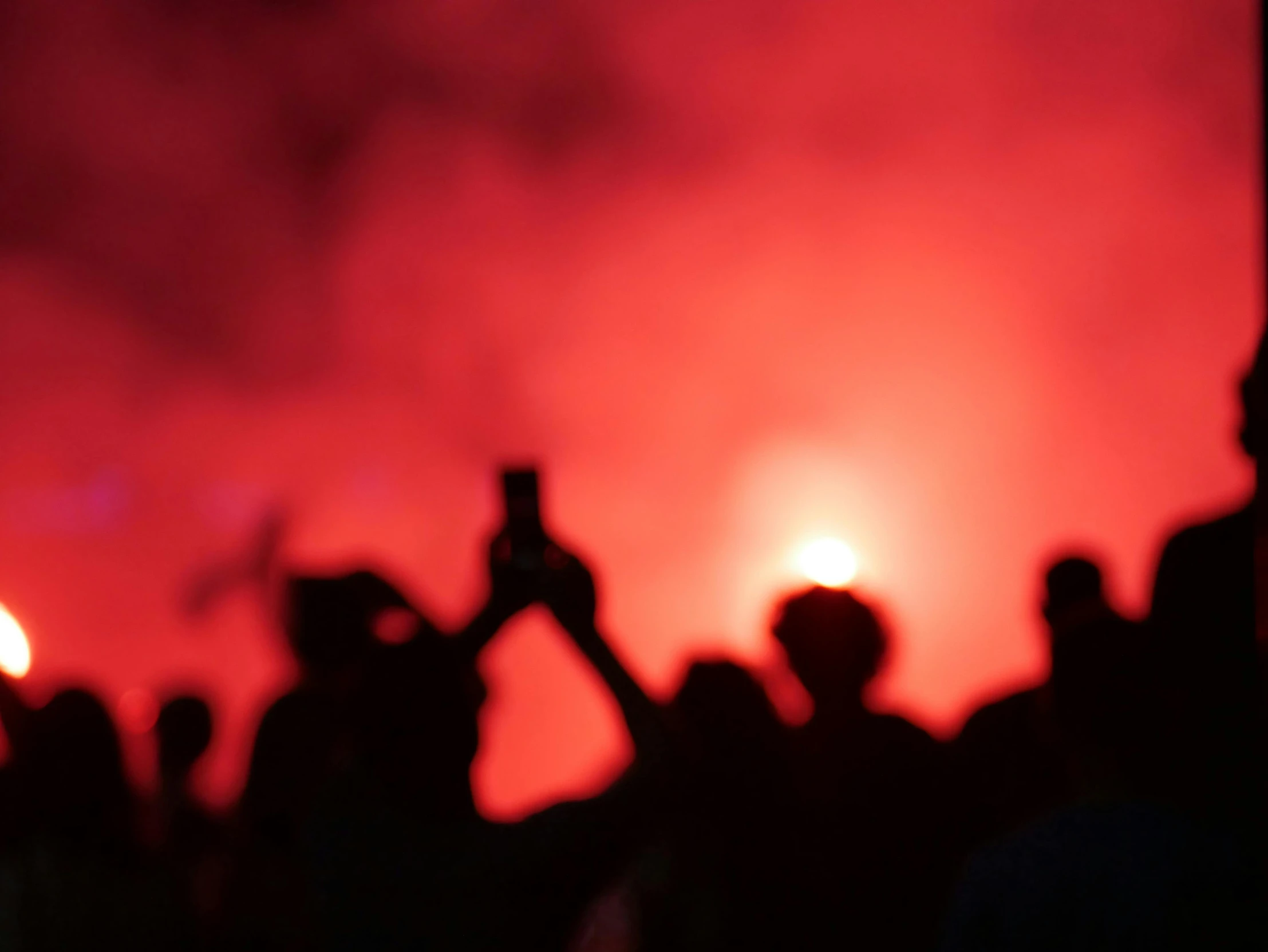 people in silhouette with their cell phones raised during a show