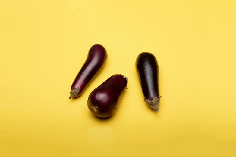 three eggplants on a yellow background, pexels, taken with sony alpha 9, hegre, ignant, 6 pack