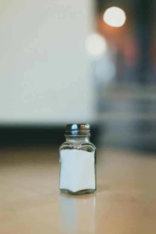 a salt shaker sitting on top of a wooden table, a picture, by Andrew Domachowski, unsplash, square, made of glazed, diner, poison