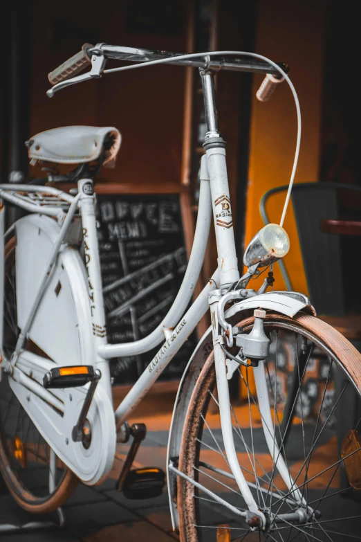 a white bicycle parked in front of a blackboard, profile image, browns and whites, up close, multiple stories