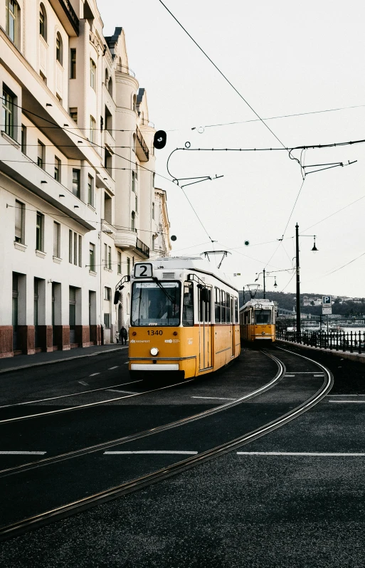 a yellow train traveling down a street next to tall buildings, by Tobias Stimmer, unsplash contest winner, viennese actionism, trams ) ) ), austro - hungarian, rounded lines, blonde