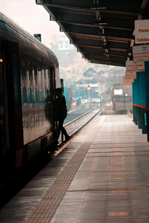 a train pulling into a train station next to a platform, by irakli nadar, lone person in the distance, square, brown, parallax »