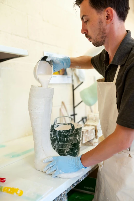 a man is making a vase out of clay, a silk screen, by David Brewster, instagram, process art, prosthetic leg, white, fluid bag, commercially ready